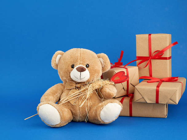 beigefarbener Teddybär und ein Stapel Kisten in braunes Kraftpap gewickelt - Foto, Bild