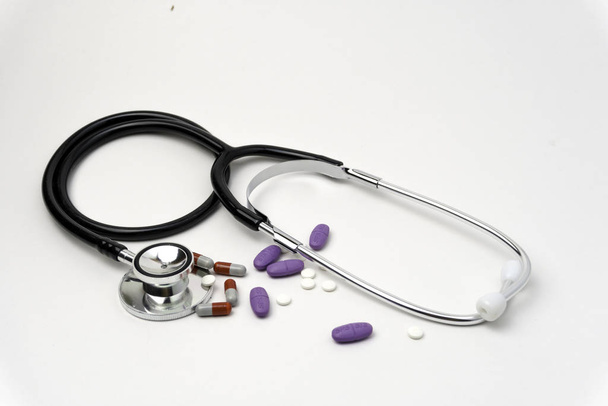Lékařský, medicínský stetoskop a pilulky na bílém pozadí. Zdravotní péče nebo nemoc. Tableta nebo lék v nemocnici nebo v lékárně. Srdeční léčba. Předpis léků - Fotografie, Obrázek
