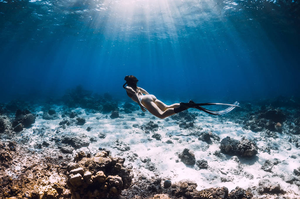 Vrouwenvrije duiker met vinnen glijdt onder water in diepblauwe oceaan - Foto, afbeelding