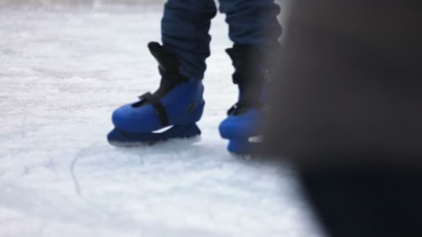 a criança em patins de gelo azuis está tentando patinar em patins de gelo em câmera lenta - close-up
 - Filmagem, Vídeo