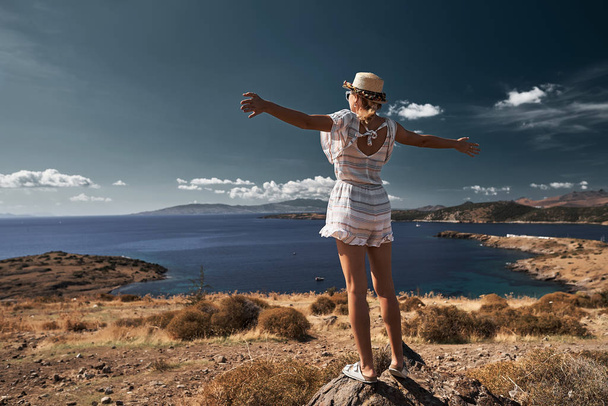 молодая женщина путешественница, стоящая на камне и поднимающая руки
 - Фото, изображение