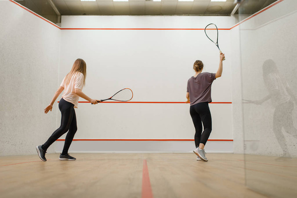 zwei weibliche Spieler mit Schlägern, Squash-Spiel auf dem Platz. Mädchen über Training, aktives Sport-Hobby, Fitness-Workout - Foto, Bild