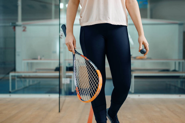 Vrouwelijke persoon toont squash racket en bal. Meisje op spel training, actieve sport hobby op het veld - Foto, afbeelding