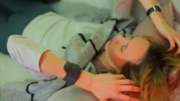 A relaxed girl is lying on a sofa with her hands on her hair. - Imágenes, Vídeo