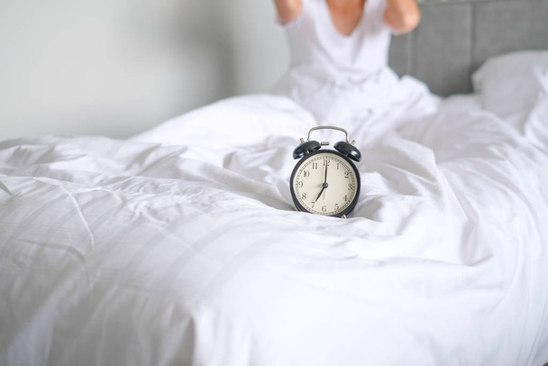 Жінка спить на ліжку вимикає будильник, прокидається вранці, вибірковий фокус
 - Фото, зображення