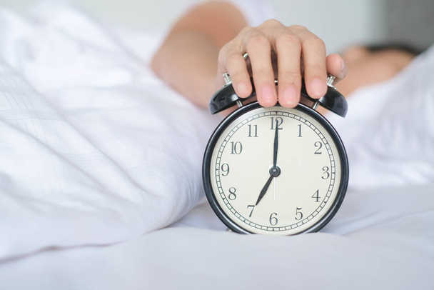 Woman sleep on the bed turns off the alarm clock wake up at the morning, Selective focus - Φωτογραφία, εικόνα