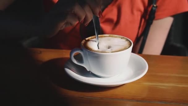 Cappuccino. Hand spoon stirs sugar in a cup of cappuccino. - Felvétel, videó