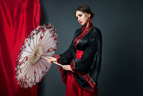 Woman is dressed in red Chinese Japanese folk clothing. Flying f - 写真・画像