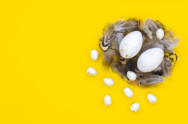 Trendy Easter flat lay with quail and chicken eggs in a nest. isolated on a yellow background. Copy space - Fotoğraf, Görsel