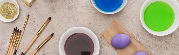 vista superior de ovos de galinha, brilho e tintas aquarela com pincéis na superfície de concreto cinza, tiro panorâmico
 - Foto, Imagem