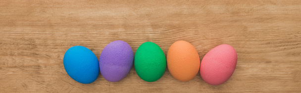 top view of rainbow painted Easter eggs on wooden table, panoramic shot - Fotoğraf, Görsel