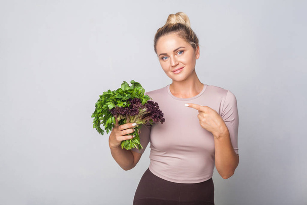 Young happy girl pointing at fresh cooking herbs, leafy green ve - Foto, Imagem