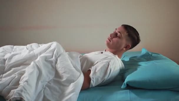 Jongeman gaat naar bed, valt in slaap in een comfortabel bed. Slapende man - Video