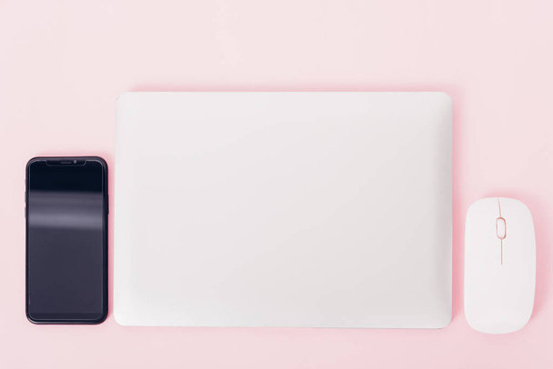 Top view of modern technology smart phone mobile and computer laptop close cover on pink background with copy space - Φωτογραφία, εικόνα