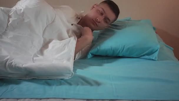 Jongeman maakt zich klaar om te slapen op het bed close-up. Gezond slapen - Video