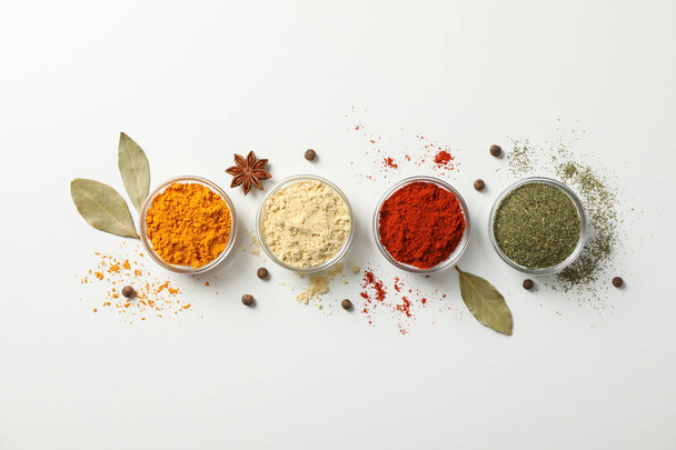 Bowls with different spices on white background, top view - Foto, afbeelding