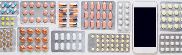 Smartphone with a dark screen. Background of colored pills. The concept of online drugstores. Copy space. - Foto, imagen