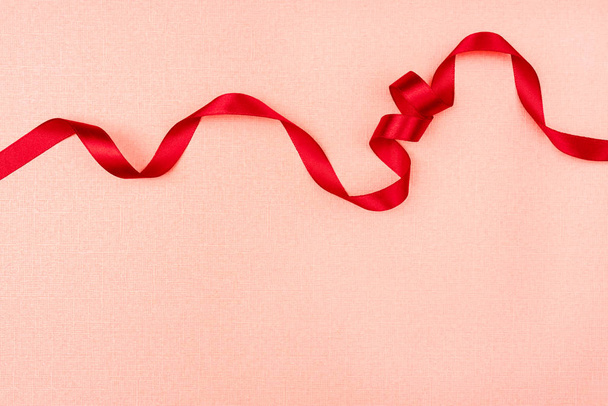 Red wavy ribbon on pink background. Holiday decoration. Valentin - Foto, imagen