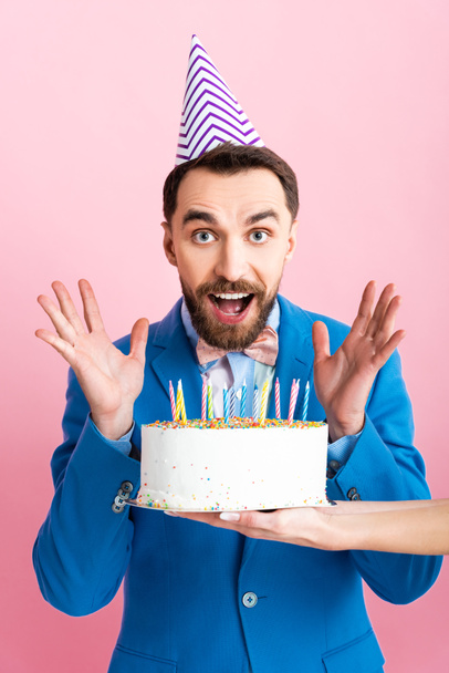 cropped view of businesswoman holding birthday cake near excited businessman isolated on pink  - Foto, imagen