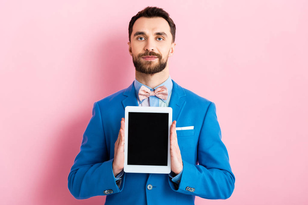 handsome businessman holding digital tablet with blank screen on pink  - Zdjęcie, obraz