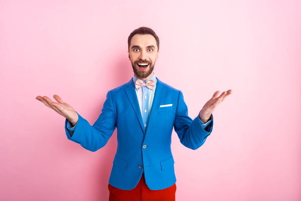 excited businessman with outstretched hands looking at camera on pink  - Фото, зображення