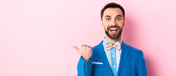 panoramic shot of happy businessman pointing with finger on pink  - Foto, afbeelding