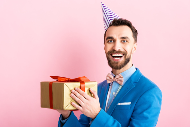 happy businessman in suit holding present on pink  - Foto, imagen