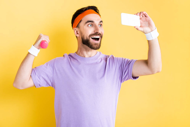 heureux sportif barbu prenant selfie et tenant haltère rose sur jaune
 - Photo, image