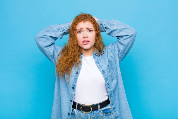 young red head woman feeling frustrated and annoyed, sick and tired of failure, fed-up with dull, boring tasks against blue wall - Foto, Imagem