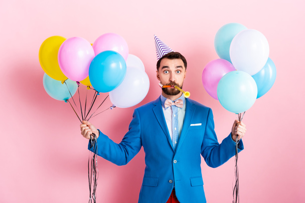 ピンクの風船を持っているパーティーキャップのビジネスマン  - 写真・画像