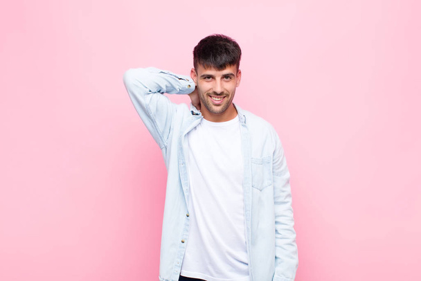 young handsome man laughing cheerfully and confidently with a casual, happy, friendly smile against pink wall - Фото, зображення