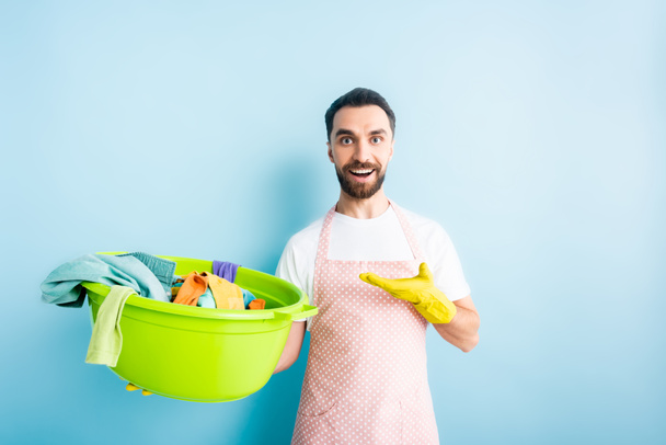 Pozitif sakallı bir adam kirli çamaşırları mavi üzerine işaret ediyor.  - Fotoğraf, Görsel