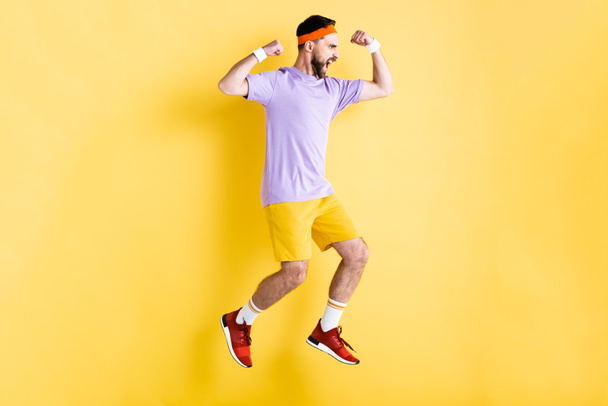 side view of excited bearded sportsman jumping on yellow - Φωτογραφία, εικόνα