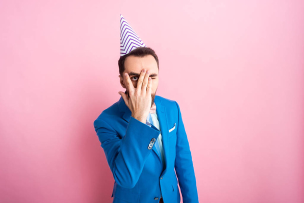 businessman in party cap covering face on pink  - Foto, imagen