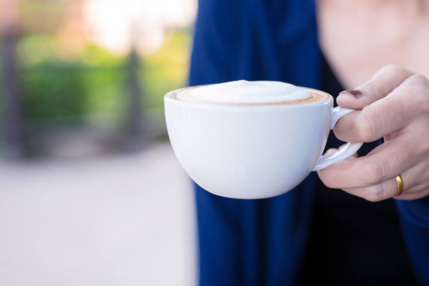 公園でコーヒーアート屋外のカップを保持する女性の手の閉じる。休暇の時間概念 - 写真・画像