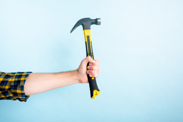 cropped view of workman holding hammer isolated on blue  - Foto, Imagem