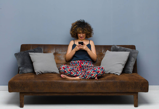 νεαρή όμορφη γυναίκα στο σπίτι, με ένα κινητό τηλέφωνο, φορώντας πιτζάμες - Φωτογραφία, εικόνα