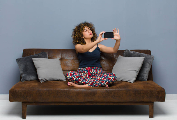 young pretty woman at home, with a mobile phone, wearing pajamas - Foto, Imagen