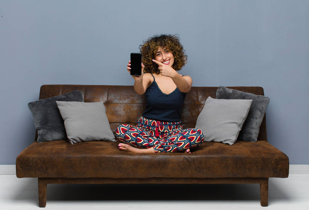 young pretty woman at home, with a mobile phone, wearing pajamas - Photo, image