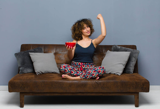 young pretty woman at home sitting on a sofa and having a breakfast - Foto, Imagen