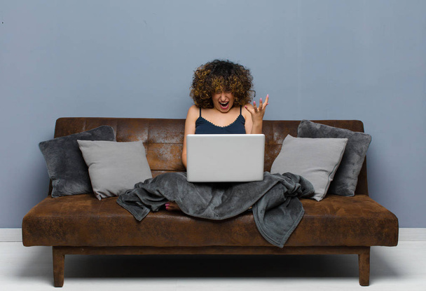 young pretty woman at home, sitting on a sofa with a laptop - Фото, изображение