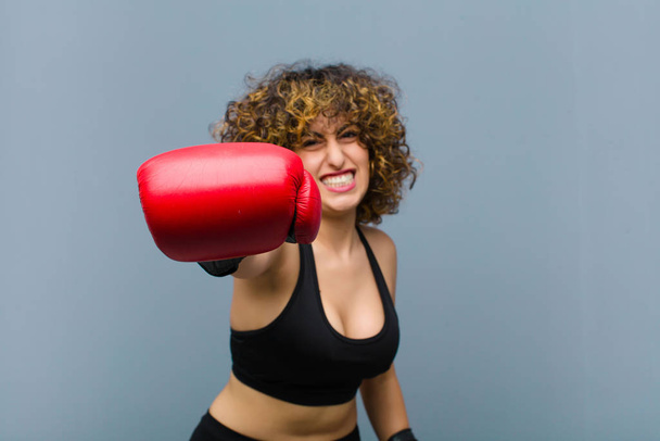 young pretty sports woman wearing fitness clothes and boxing gloves - Фото, изображение