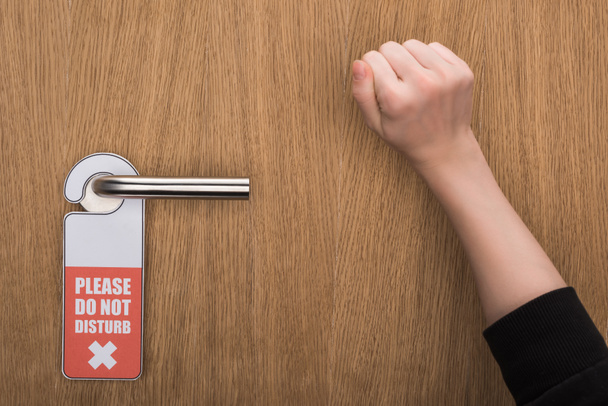 vista recortada de la mujer llamando a la puerta con por favor no molestar signo
  - Foto, Imagen