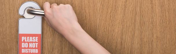 vista parcial de la mujer sosteniendo la manija de la puerta con por favor no molestar signo, tiro panorámico
 - Foto, imagen