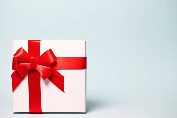 Present box  wrapped with red ribbon on colorful background. Fes - Photo, Image