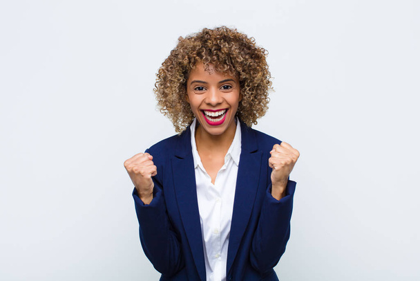 young woman african american feeling shocked, excited and happy, laughing and celebrating success, saying wow! against flat wall - Zdjęcie, obraz