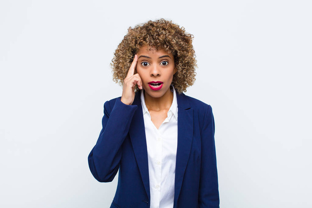 young woman african american looking surprised, open-mouthed, shocked, realizing a new thought, idea or concept against flat wall - Фото, изображение