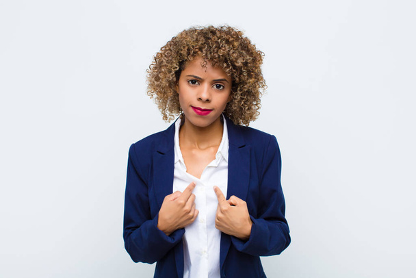 young woman african american pointing to self with a confused and quizzical look, shocked and surprised to be chosen against flat wall - Zdjęcie, obraz