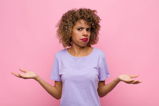 young african american woman looking puzzled, confused and stressed, wondering between different options, feeling uncertain against pink wall - Φωτογραφία, εικόνα