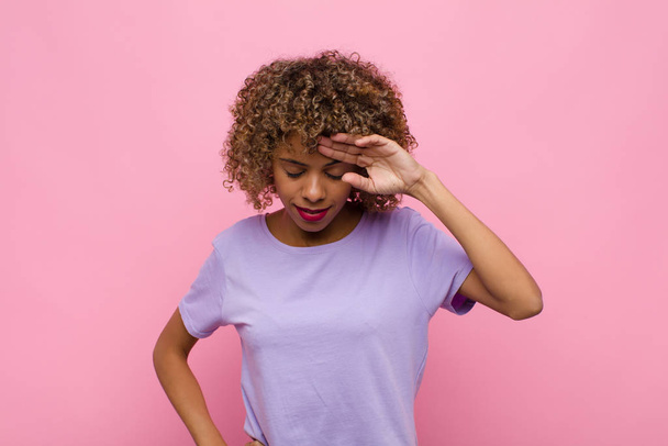young african american woman looking stressed, tired and frustrated, drying sweat off forehead, feeling hopeless and exhausted against pink wall - Foto, Imagen